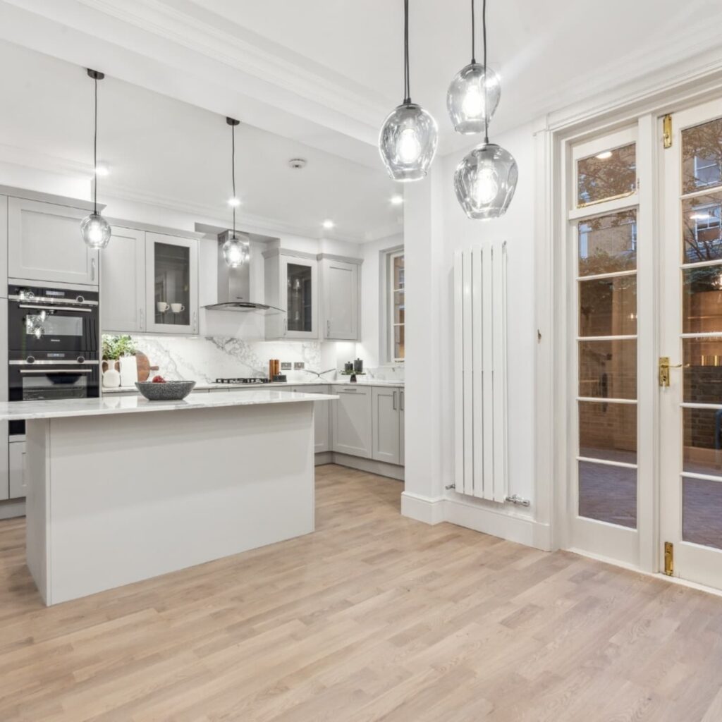 Open-plan kitchen with island, pendant lighting and timber flooring in Pimlico SW1