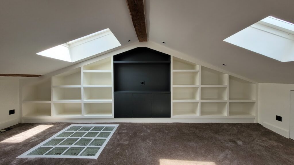 Bespoke library shelving beneath a sloping ceiling and timber beams in Versailles